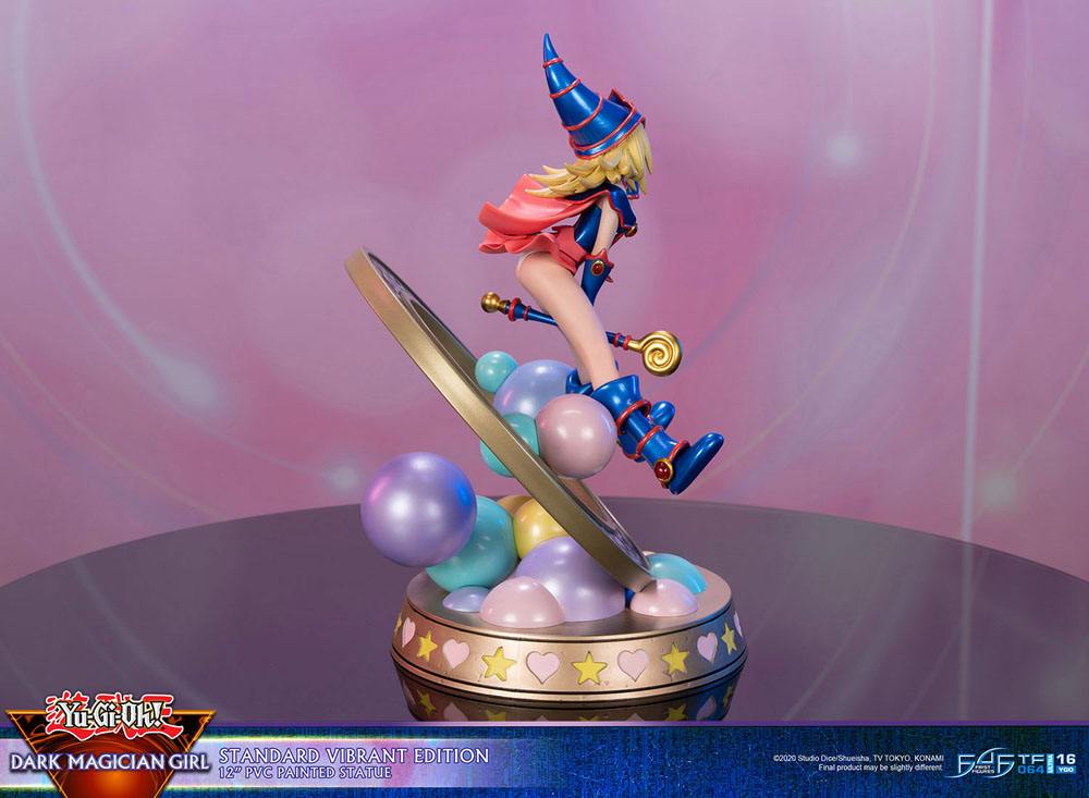 Figurine de Dark Magician Girl en PVC, posée dans un cercle magique décoré de runes, avec des sphères pastel à la base. Elle porte sa tenue bleue et rose emblématique, avec un chapeau pointu et une pose dynamique.
