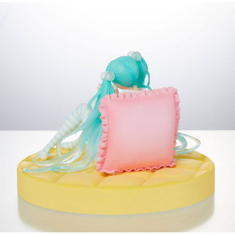 Figurine de Hatsune Miku en tenue pastel décontractée, assise avec une tasse dans les mains, ambiance cosy et kawaii.