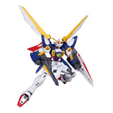 Maquette Gunpla HG 1/144 Wing Gundam avec ailes jaunes et blanches, fusil, bouclier et pose dynamique sur fond blanc.