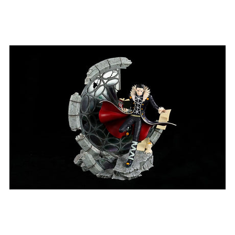 Statue Kuroro Lucilfer 33 cm Hunter x Hunter en édition limitée, posée devant un décor en ruines circulaires.