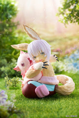 Figurine Nanachi et Mitty assises dans un décor verdoyant issue de Made in Abyss avec une pose tendre et protectrice