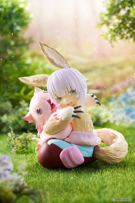 Figurine Nanachi et Mitty assises dans un décor verdoyant issue de Made in Abyss avec une pose tendre et protectrice