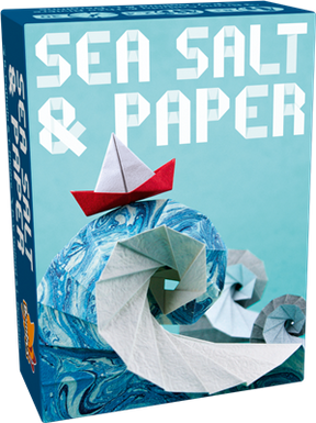 Boîte du jeu Sea Salt & Paper avec vague en origami bleu et blanc et petit bateau en papier rouge sur fond bleu.